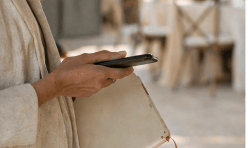 Una planificadora con el móvil sobre un cuaderno abierto, con el lugar de la celebración al fondo
